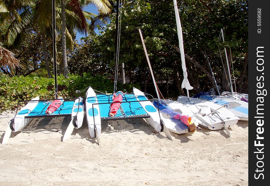 A line of sail boats on the sandy beach waiting to be used. A line of sail boats on the sandy beach waiting to be used.