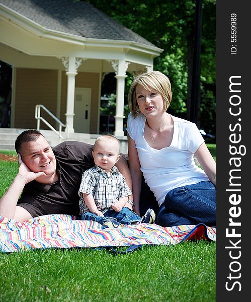 A happy family lying on a picnic mat on the grass. - vertically framed. A happy family lying on a picnic mat on the grass. - vertically framed