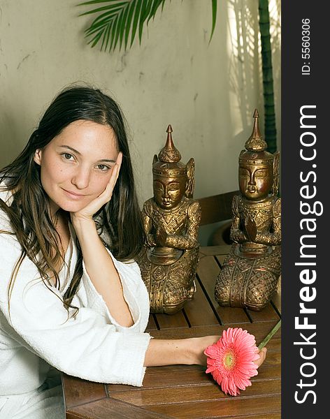 A Young girl smiling by two statues with a pink flower in her hand. - vertically framed. A Young girl smiling by two statues with a pink flower in her hand. - vertically framed