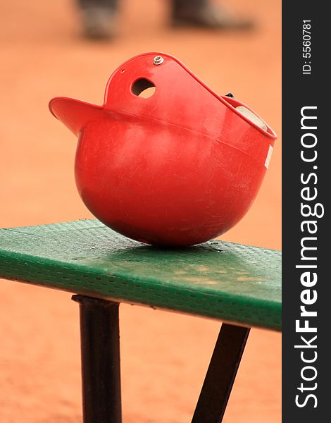 Still life of a red Baseball helmet sitting on a bench