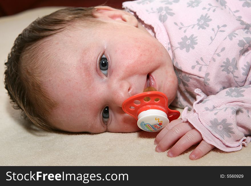 A new born baby with a pacifier in her mouth. A new born baby with a pacifier in her mouth