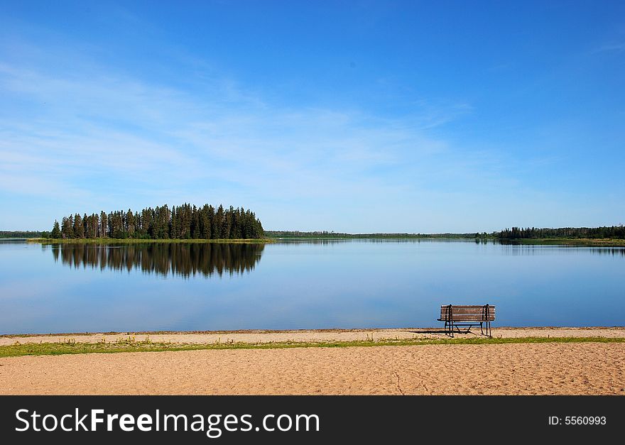 Island in the lake and a bench on the beach