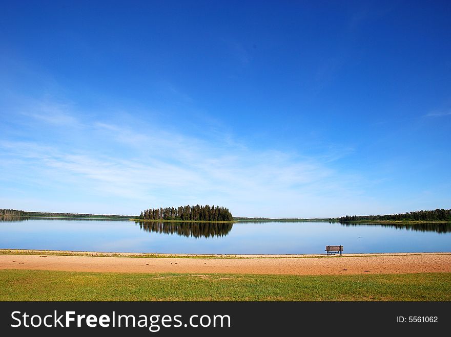 Island in the lake and a bench on the beach