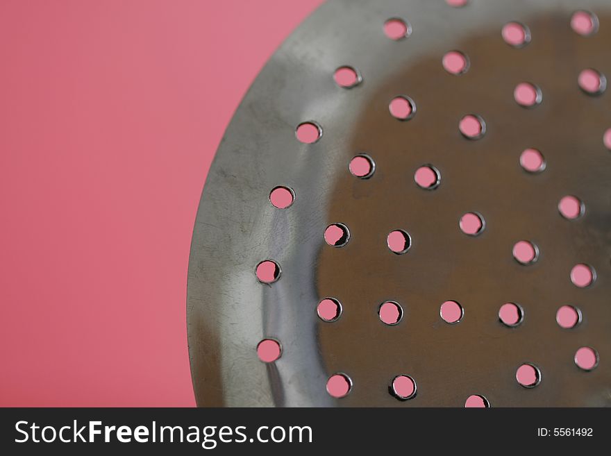 A spoon with holes in a simple color background