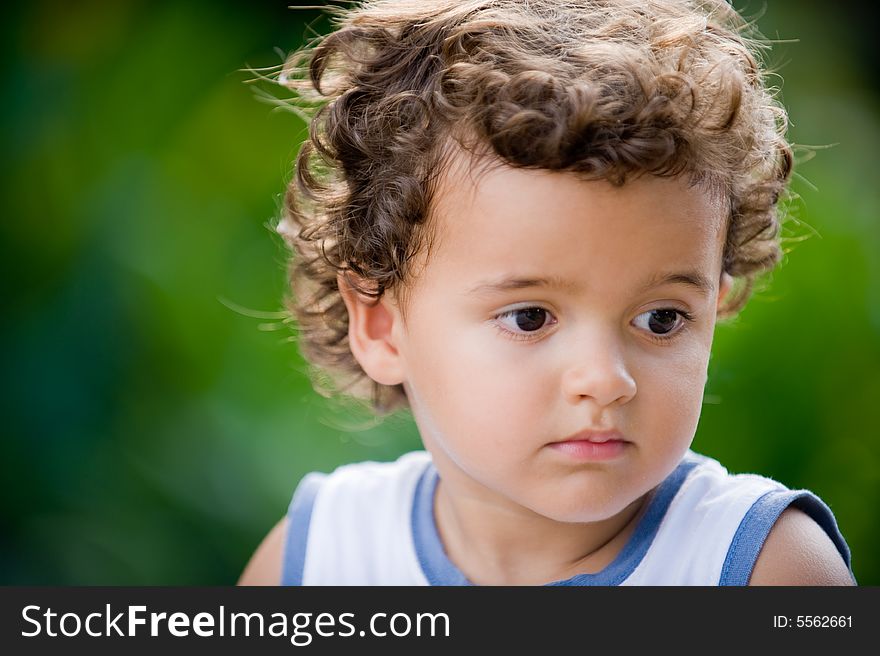 A cute young boy with curly hair in a natural setting. A cute young boy with curly hair in a natural setting