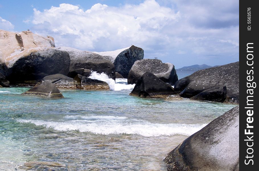 Waves crashing against large granite boulders on the beach of a paradise island. Waves crashing against large granite boulders on the beach of a paradise island.