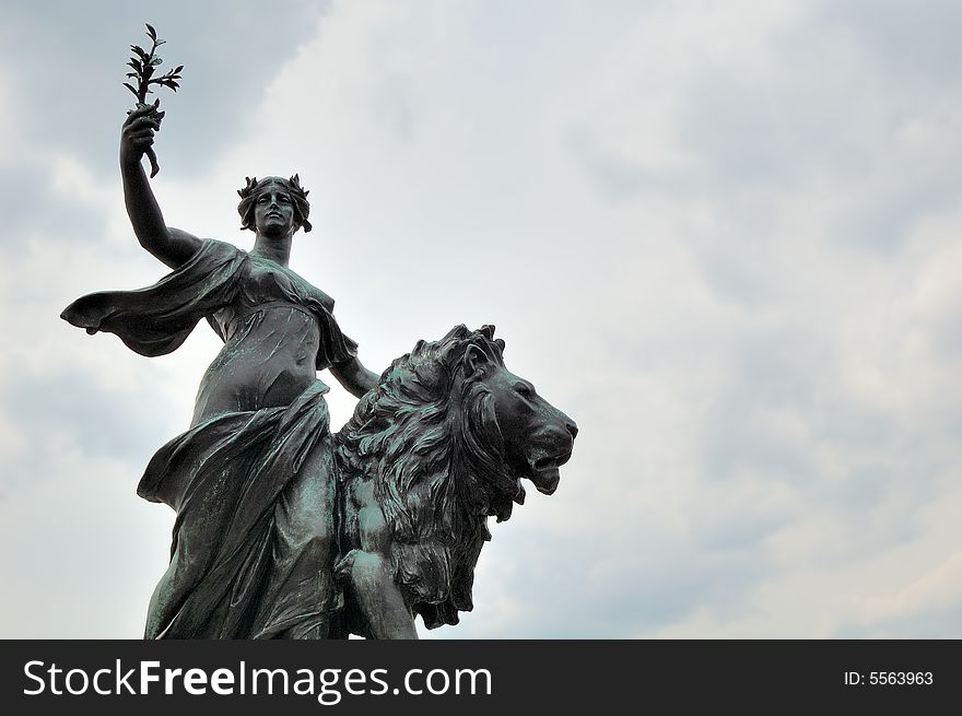 Bronze statue of a young woman raising her arm with a lion by her side. Bronze statue of a young woman raising her arm with a lion by her side