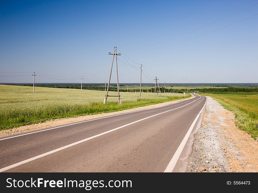 Grass meadow, blue sky and road