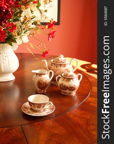 A simple arrangement of teacup and accessories on a dark wood table, perfect for an afternoon tea.