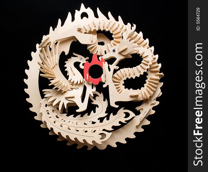 Carved an ornament - dragons from plywood slices on a black background