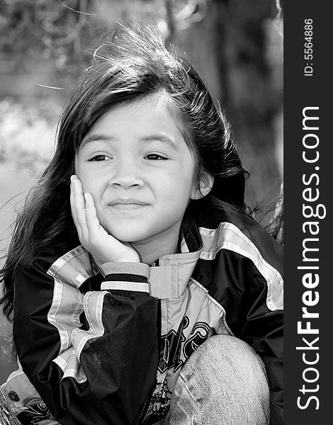 A black & white portrait of a cute young girl outside.