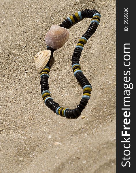 Ethnic necklace with shells on he sand of a beach. Ethnic necklace with shells on he sand of a beach.