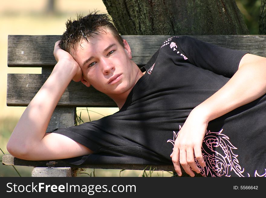 Young boy lying on a bench in the park. Young boy lying on a bench in the park.
