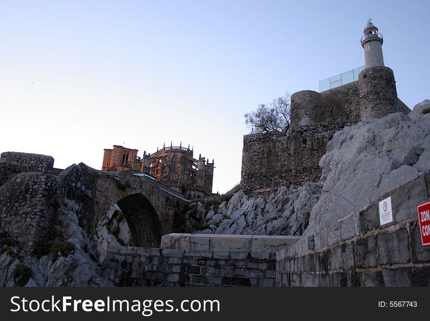 Castle with lighthouse and a gothic church in a background. Castle with lighthouse and a gothic church in a background