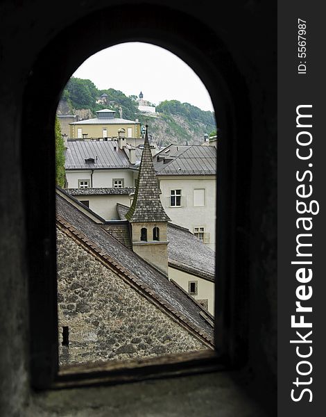 Rooftops in Salzburg, Austria seen through the silhouette of an arched window.