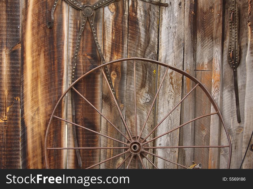 An old horse carriage wheel against a barn wall. An old horse carriage wheel against a barn wall.