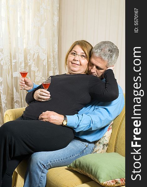 A female sits on a males lap, both drinking out of champagne glasses. - vertically framed. A female sits on a males lap, both drinking out of champagne glasses. - vertically framed