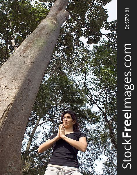 Woman Performing Yoga Next To Tree-Verical