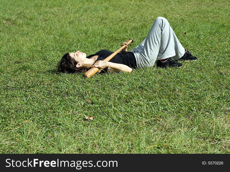 Woman Laying On Grass Holding Bat-Horizontal