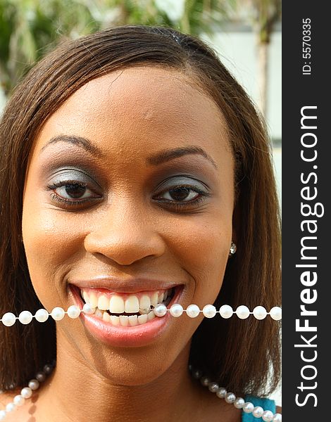 Young woman with a pearl necklace in her mouth. Young woman with a pearl necklace in her mouth.
