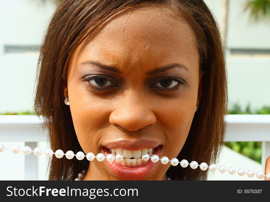 Woman with a string of pearls in her mouth.