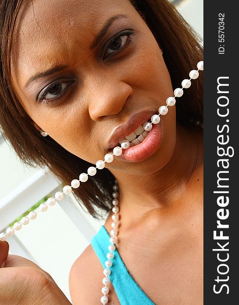 Woman with a string of pearls in her mouth.