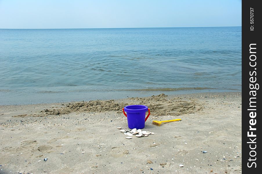 Toy bucket on sea shore with shells