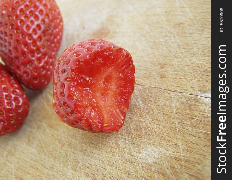 Three shiny strawberries isolated on wooden board, the front one bitten

*RAW format available