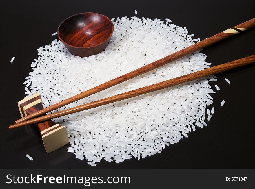 Closeup view of chopsticks and a bowl with rice on a black background. Closeup view of chopsticks and a bowl with rice on a black background