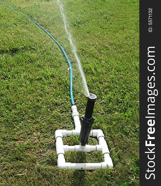 A water sprinkler on perfect green grass