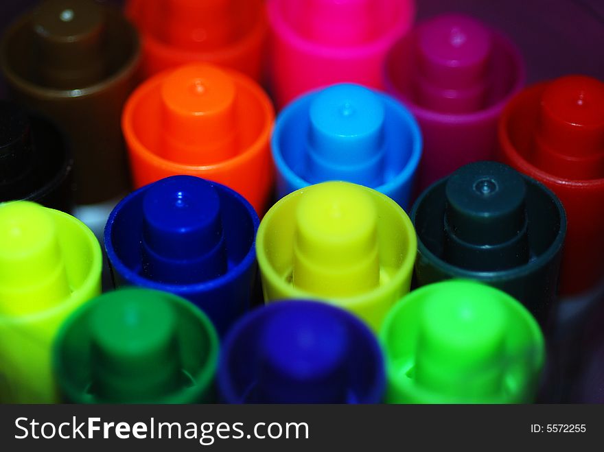 A macro photograph of a group of brightly colored pen lids. A macro photograph of a group of brightly colored pen lids