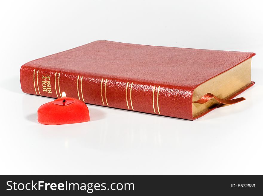 Holy Bible and a red heart-shaped candle. Holy Bible and a red heart-shaped candle