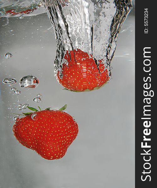 Two strawberries diving in a glass of water. Two strawberries diving in a glass of water
