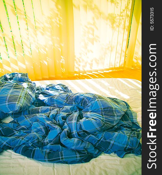 Bed with pillow and blanket in sunny morning