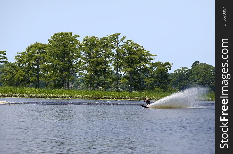 Advanced slalom water skier being pulled by a boat on a sunny day. Advanced slalom water skier being pulled by a boat on a sunny day.