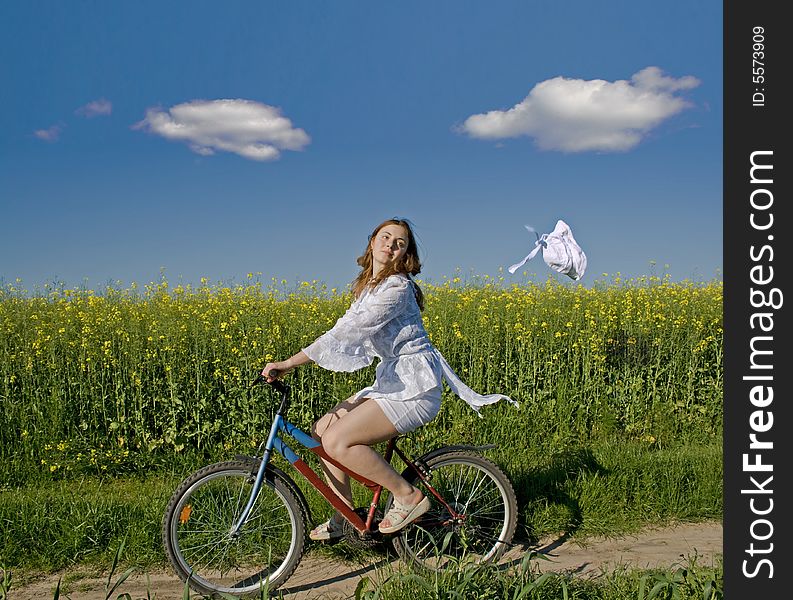 The girl goes on a bicycle and the wind breaks a hat. The girl goes on a bicycle and the wind breaks a hat