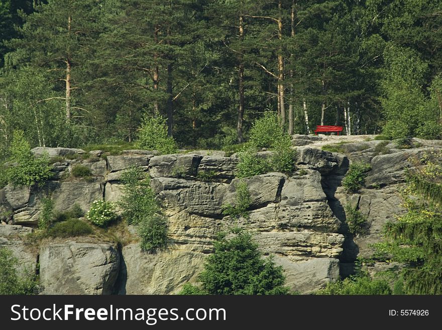 Red park bench on the rock