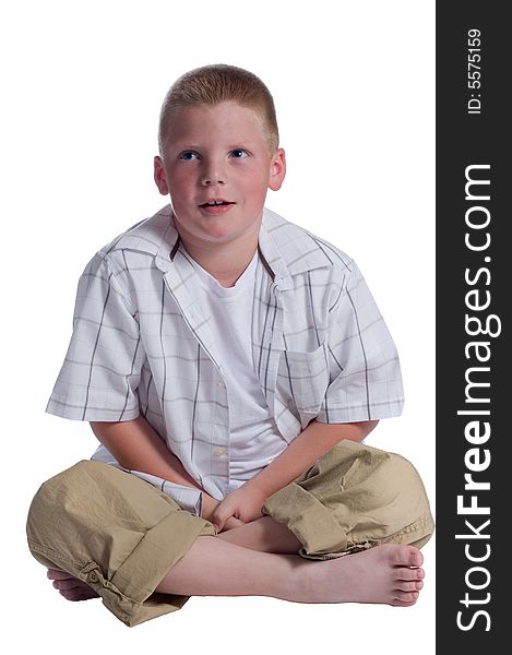 Little boy sitting cross legged on floor with eyes tilted up thinking isolated on white background. Little boy sitting cross legged on floor with eyes tilted up thinking isolated on white background