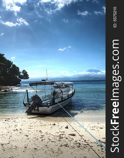 Photograph of a boat on the beach of Nusa Lembongan, a small island to the southeast of Bali, Indonesia. In the background, Mount Agung on Bali can be seen. Photograph of a boat on the beach of Nusa Lembongan, a small island to the southeast of Bali, Indonesia. In the background, Mount Agung on Bali can be seen.