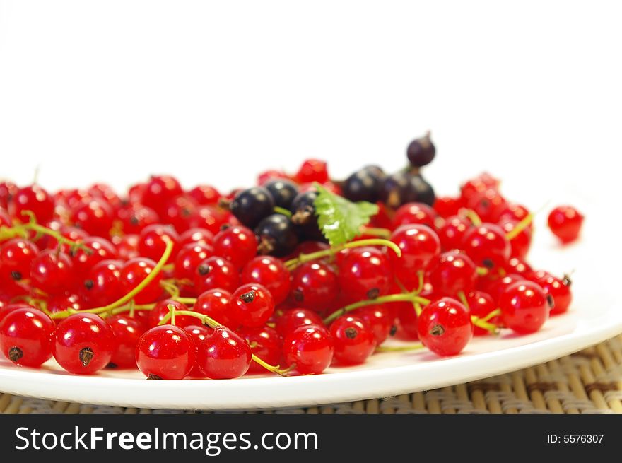 Red and black currant on a white plate