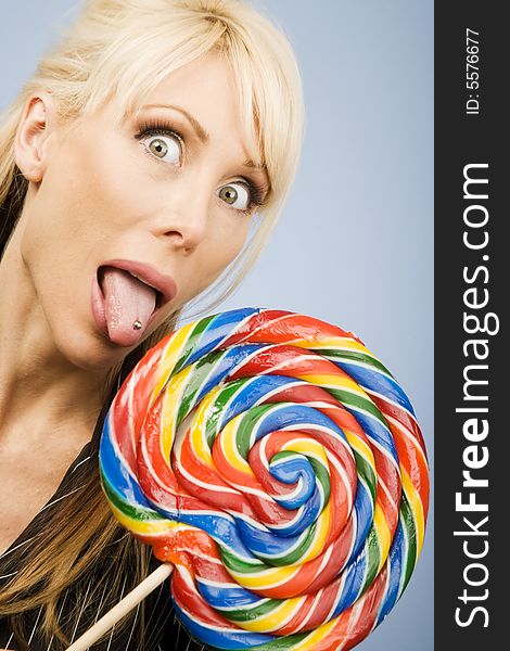 Woman with a pierced tongue licking a big colorful lollipop. Woman with a pierced tongue licking a big colorful lollipop