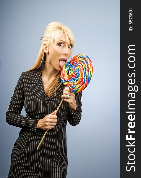 Woman with a pierced tongue licking a big colorful lollipop. Woman with a pierced tongue licking a big colorful lollipop