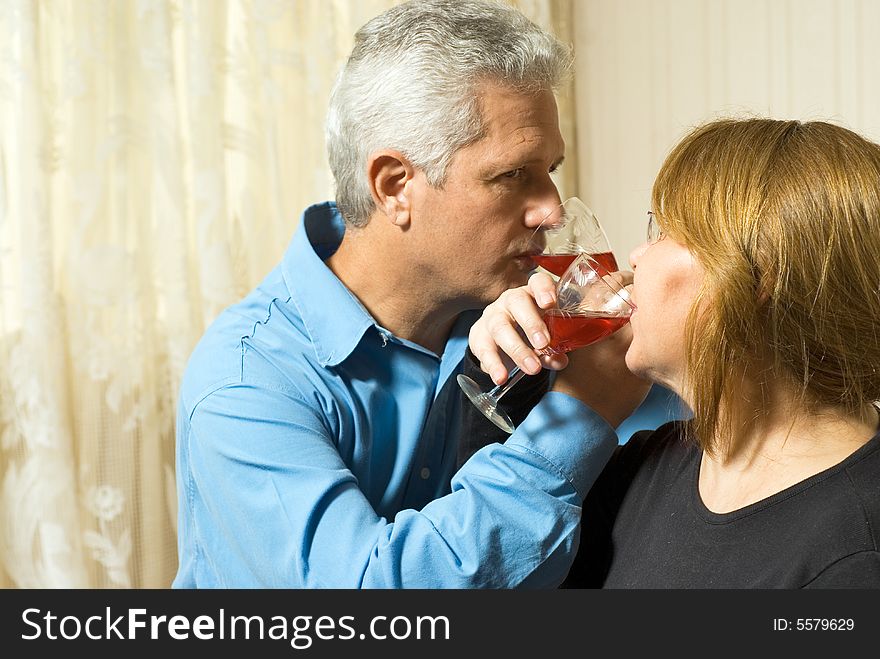 A couple crossing arms while staring at each other, drinking together. - horizontally framed. A couple crossing arms while staring at each other, drinking together. - horizontally framed