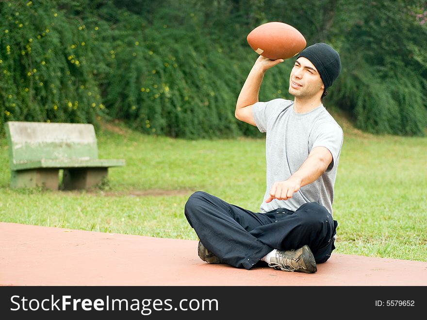 Man Sitting Throwing Football - Horizontal