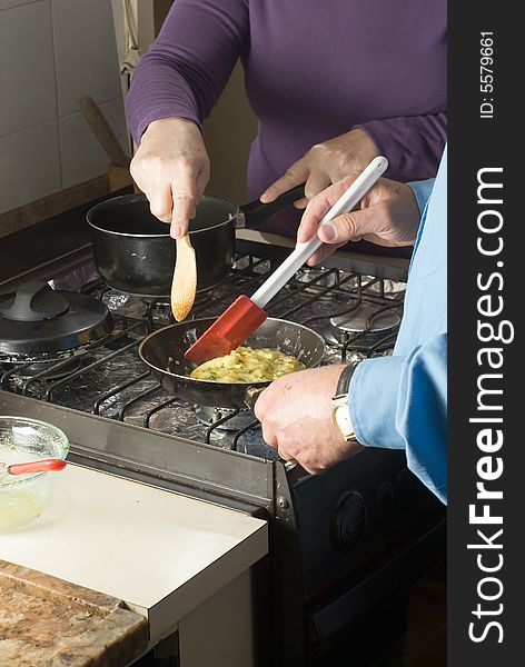 A couple make scrambled eggs over the stove, together. - vertically framed. A couple make scrambled eggs over the stove, together. - vertically framed