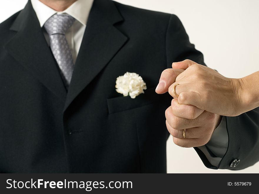 A couple hold hands tightly. The man wears a tuxedo. - horizontally framed. A couple hold hands tightly. The man wears a tuxedo. - horizontally framed