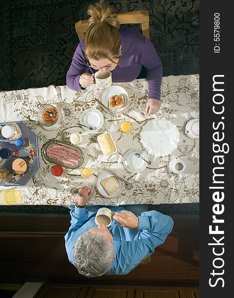 A couple eating a meal at their table.  - vertically framed. A couple eating a meal at their table.  - vertically framed