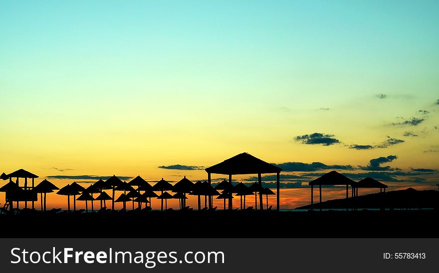 Silhouettes of beach umbrellas on the seashore at sunset, summer