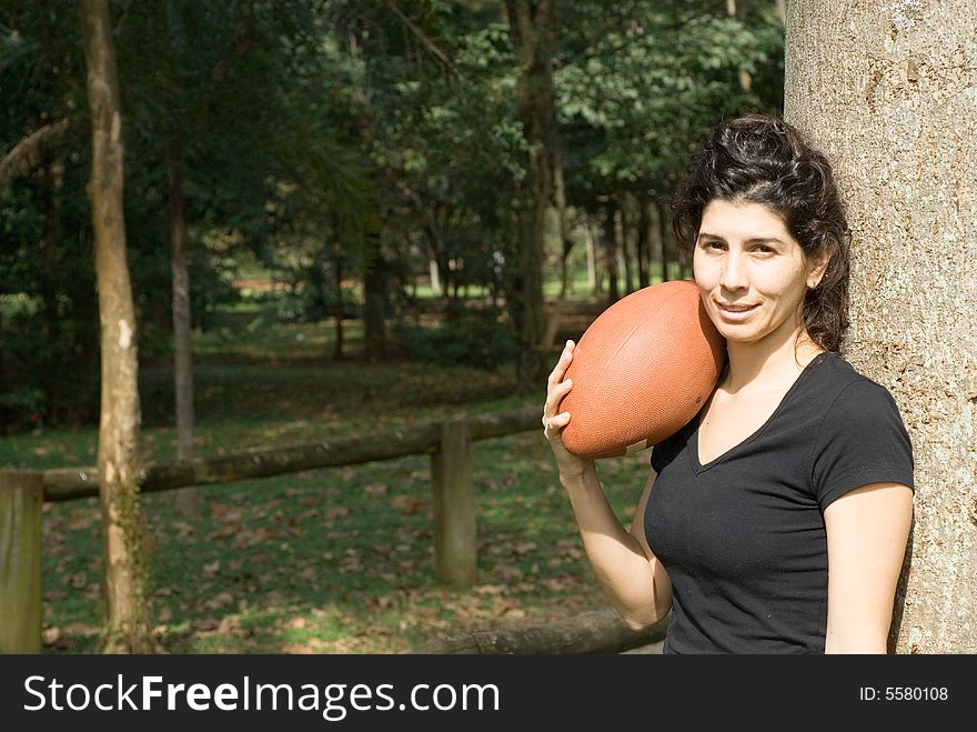 Smiling Woman Next to Tree Holding a Footba