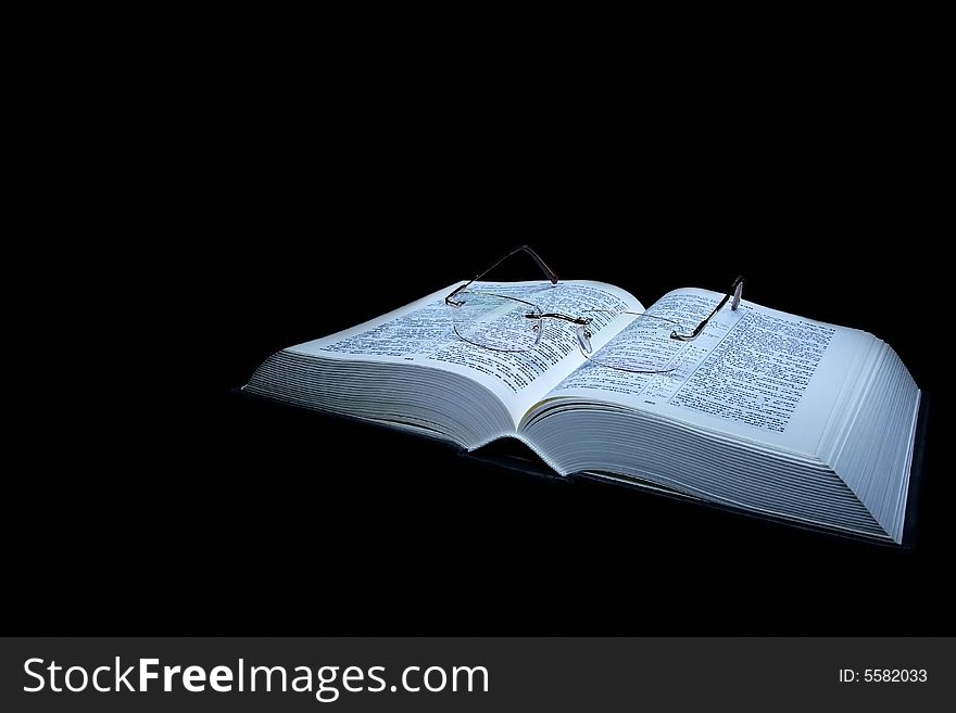 Isolated book with glasses on a black background. Isolated book with glasses on a black background